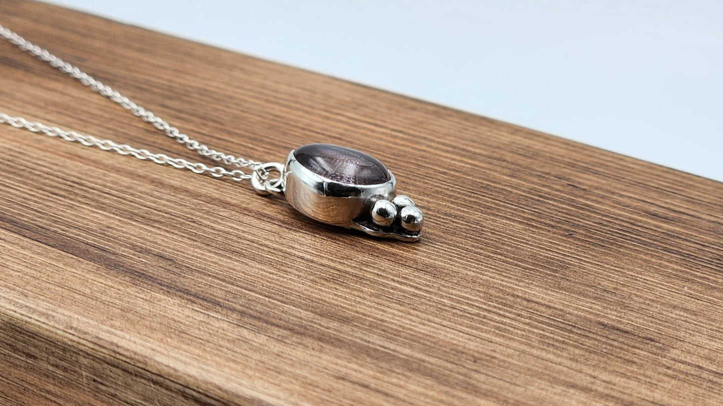 Silver necklace with a small pendant on a wooden surface