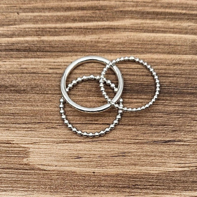 A picture of 3 sterling silver rings on a wood tray