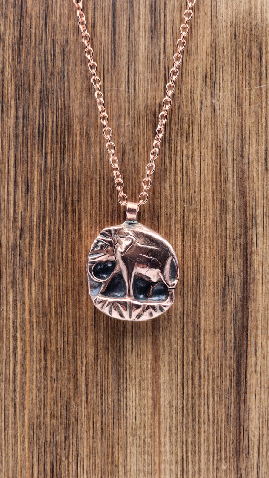 Copper Elephant pendant on a wooden surface