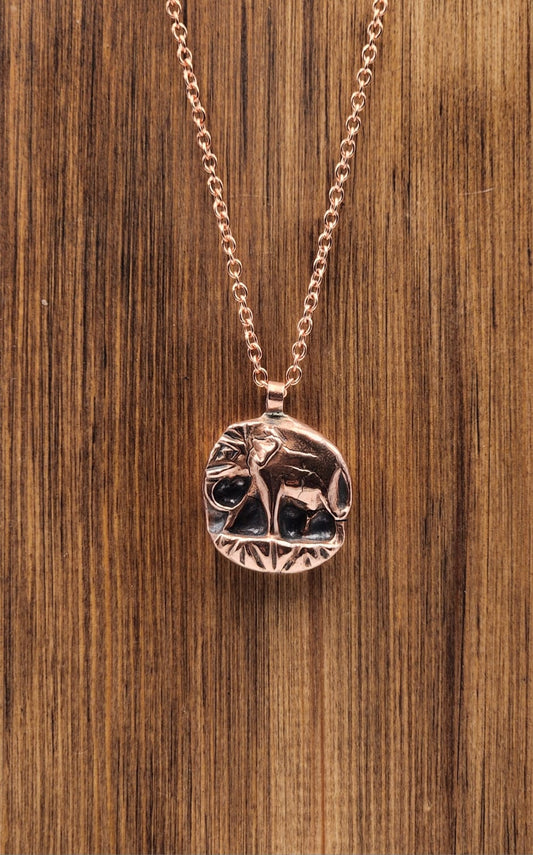 Copper necklace with a circular pendant on a wooden surface