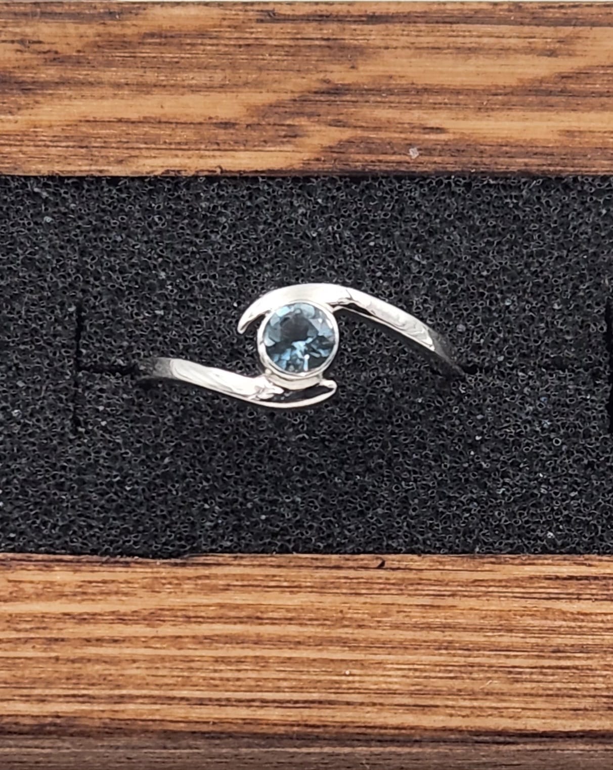 Sterling Silver Bypass ring set with a faceted Santa Maria Aquamarine gemstone shown in a ring display box