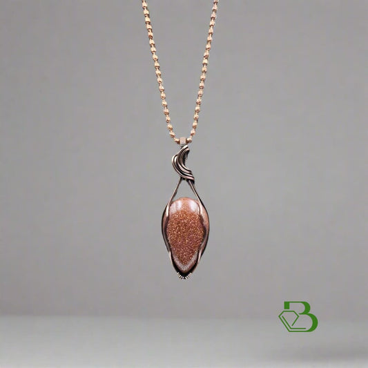 Handmade Copper Wire Pendant with goldstone on neutral background