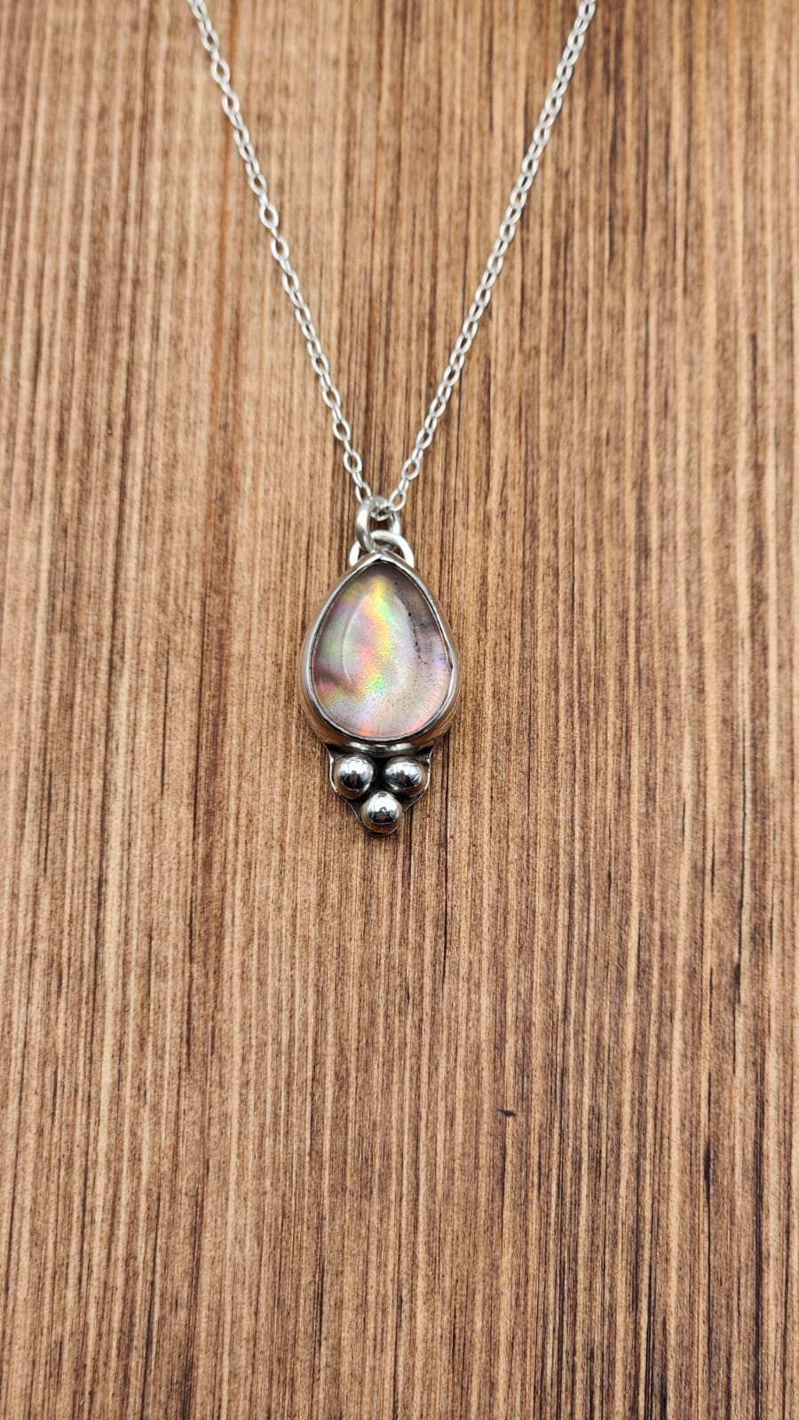 Necklace with a teardrop-shaped pendant on a wooden surface