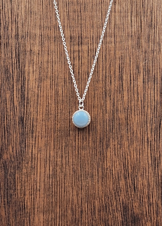 Close up of Small Sterling Silver Owyee Blue  Opal Pendant on a Wooden Display