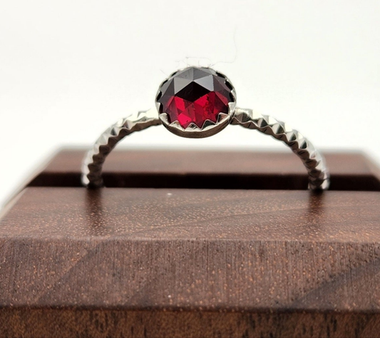 Ring with a red gemstone on a wooden surface
