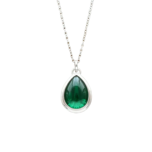 A silver teardrop pendant necklace with a green marquise-cut gemstone, displayed on a brown wooden surface.