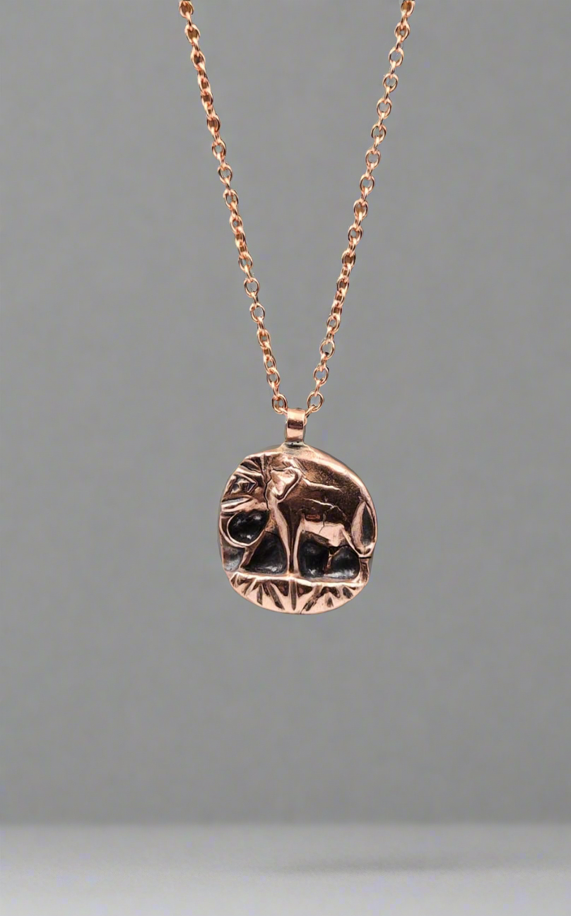 Rose gold necklace with a circular pendant on a gray background