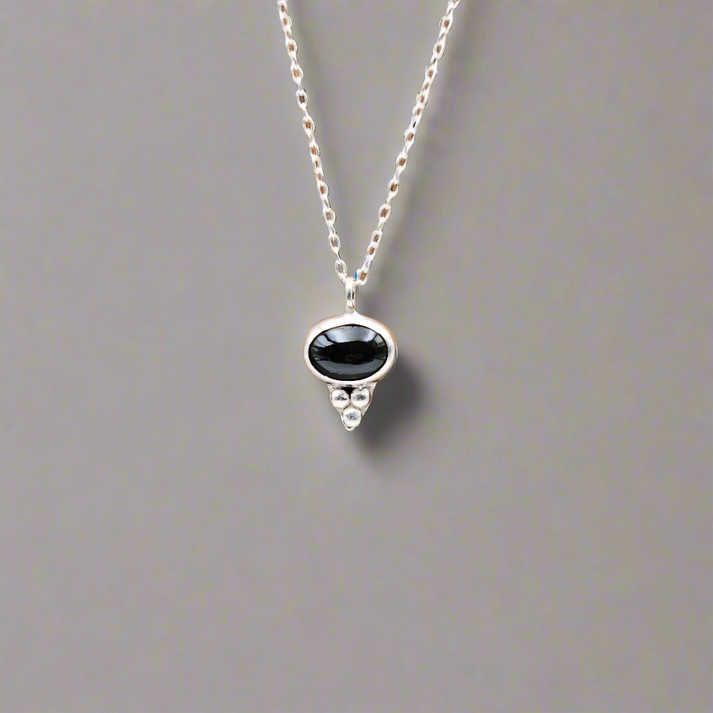 Necklace with a black gemstone pendant on a gray background