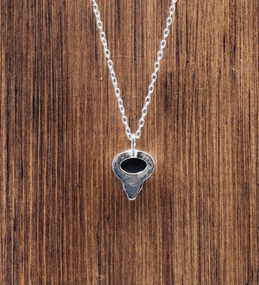 Silver necklace with a unique pendant on a wooden surface