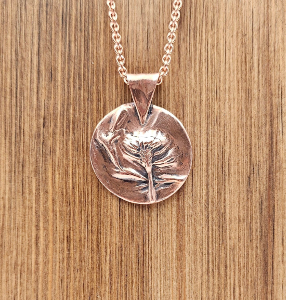 Copper Clay  necklace with a circular pendant on a wooden surface