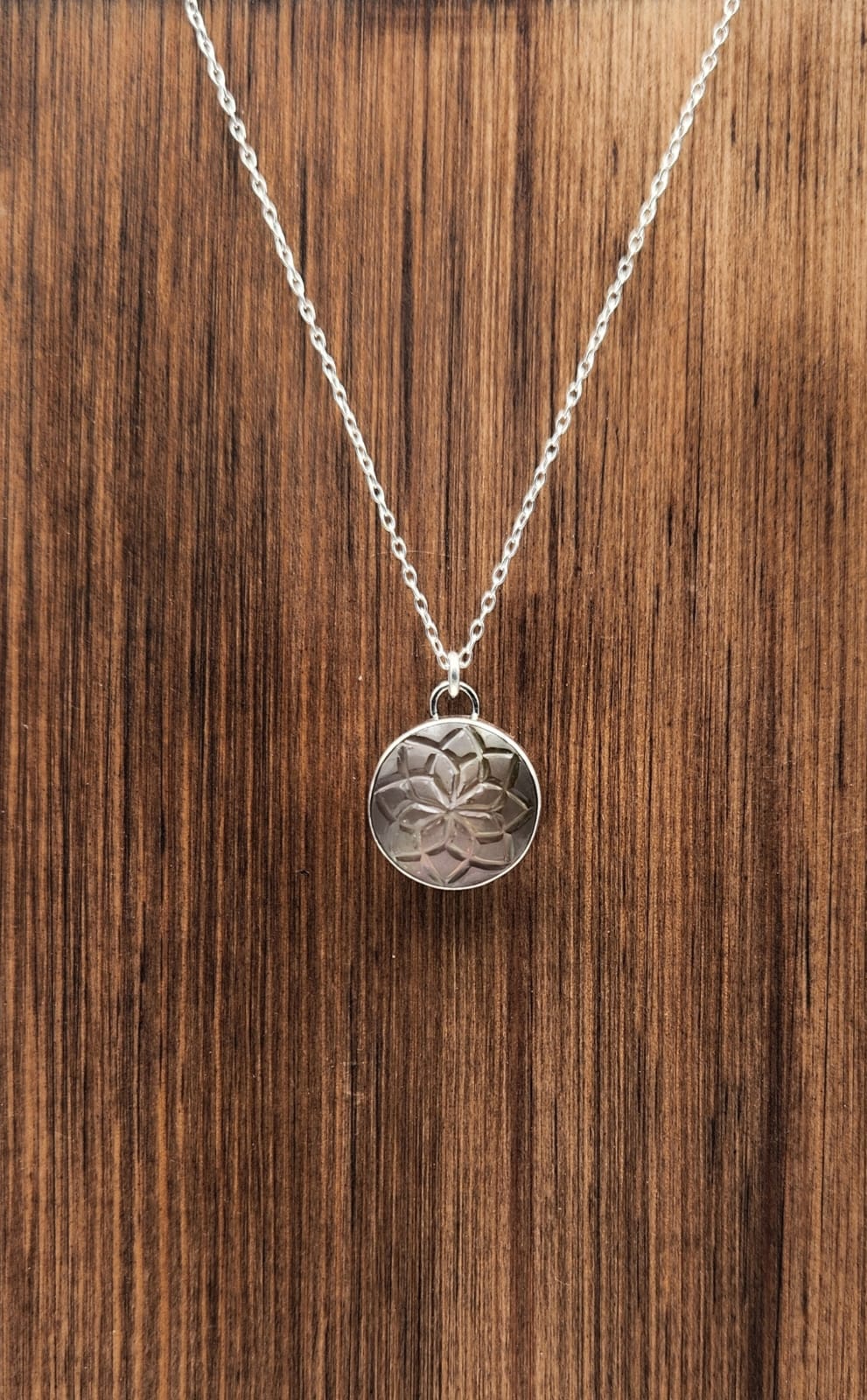 Silver necklace with a round pendant on a wooden surface