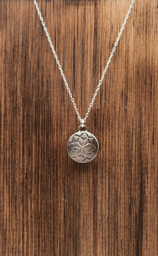 Silver necklace with a round pendant on a wooden surface