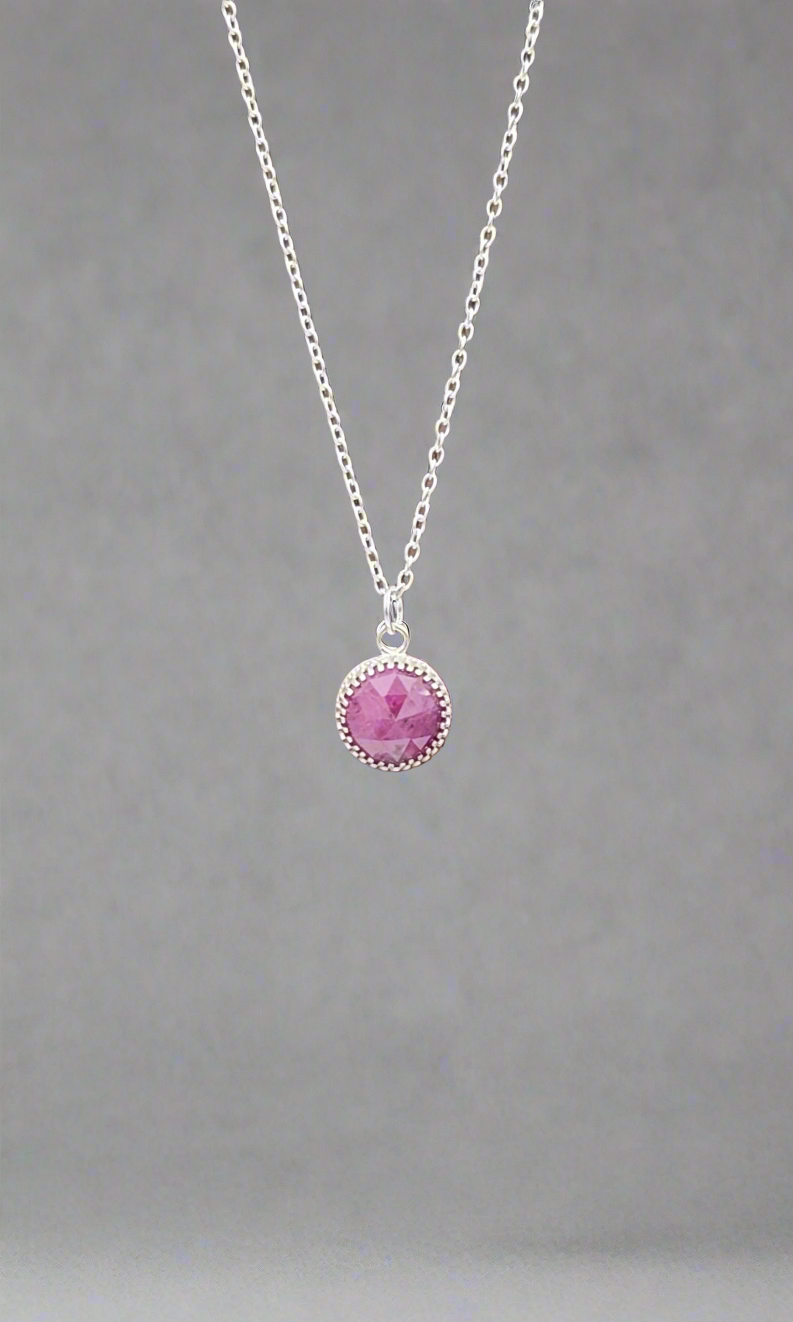 Necklace with a pink gemstone pendant on a gray background