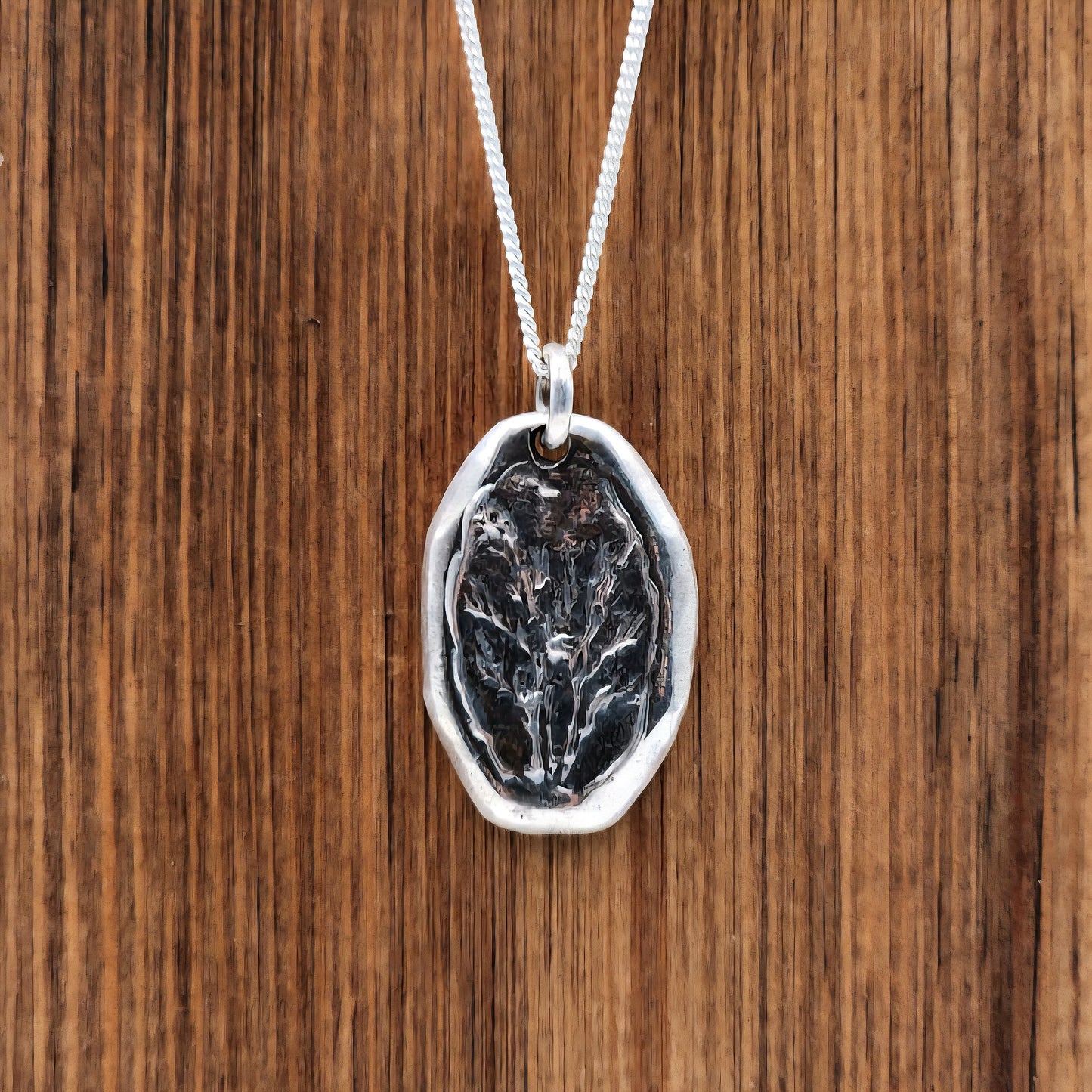 Silver pendant with a flower design on a wooden surface