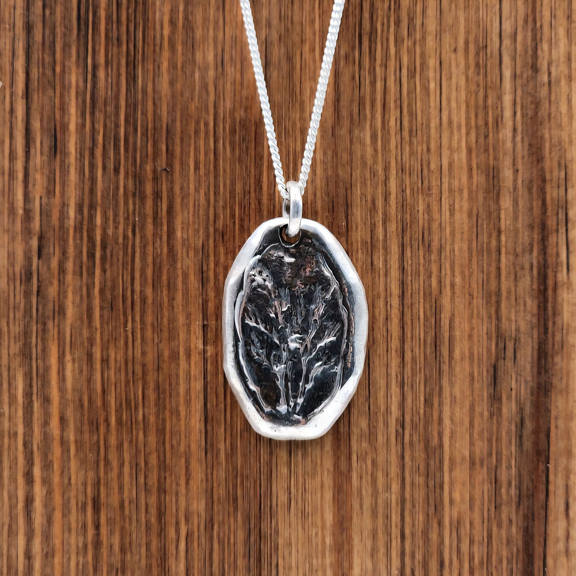 Silver pendant with a flower design on a wooden surface