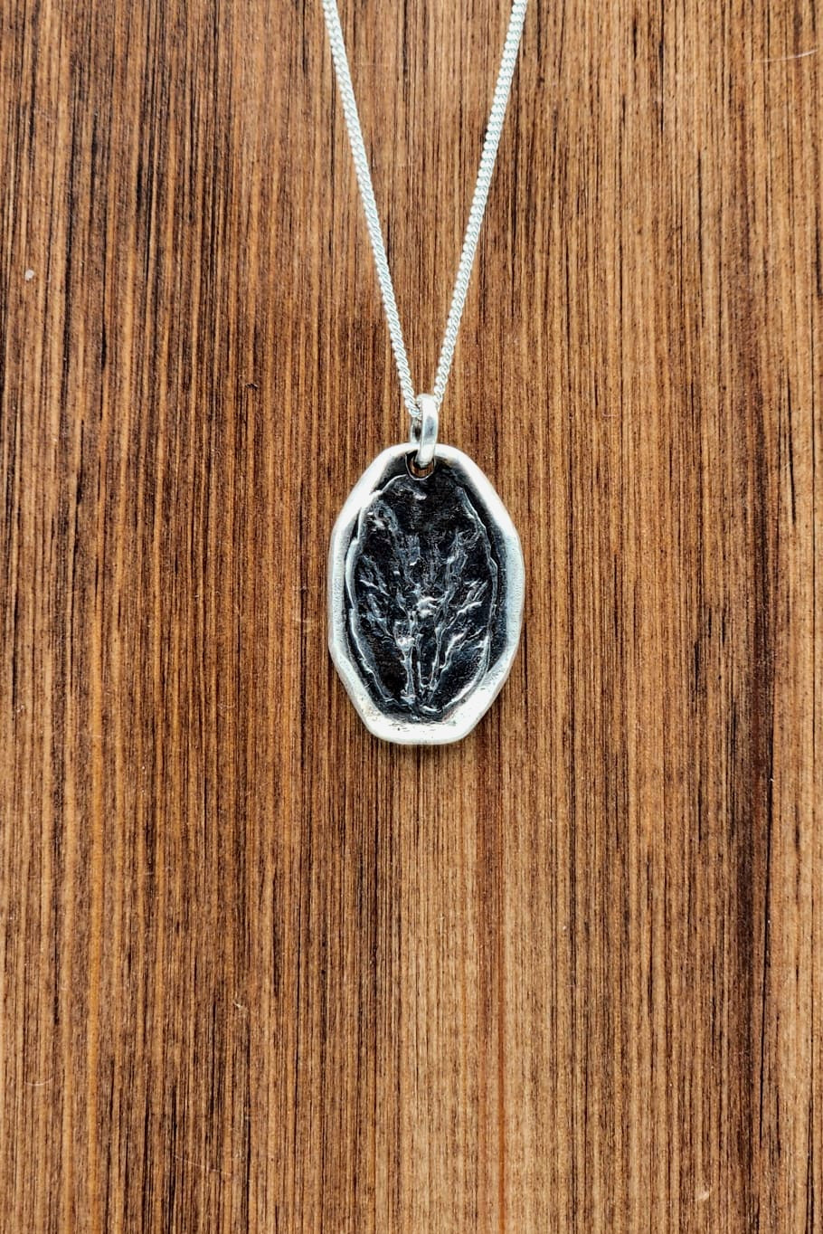 Silver pendant necklace on a wooden surface