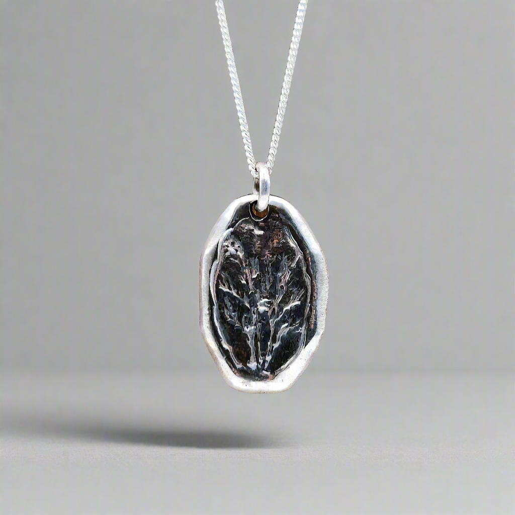 Silver pendant with a black design on a gray background