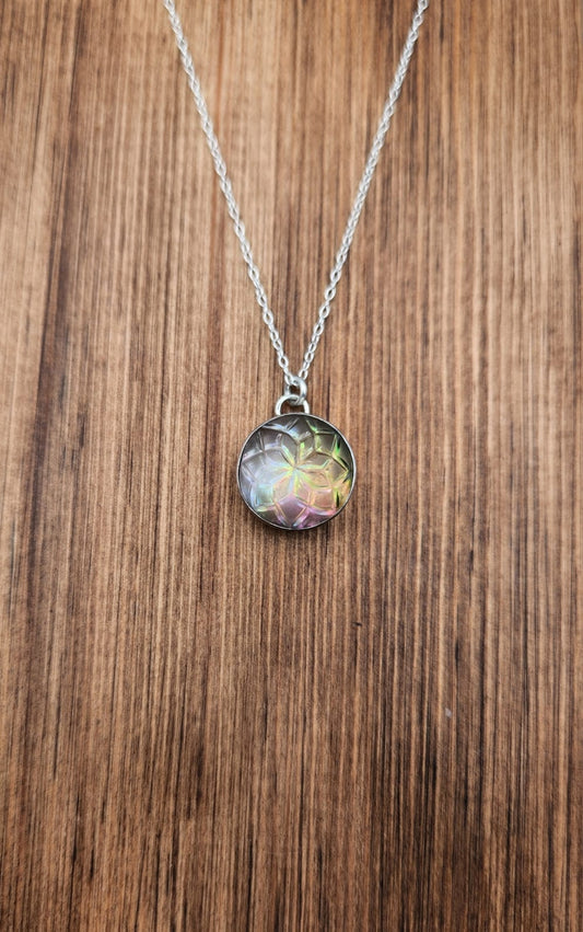 Necklace with a round, multicolored pendant on a wooden surface
