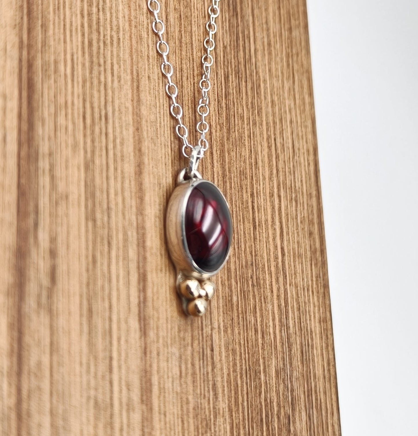 Necklace with a red stone pendant on a wooden surface