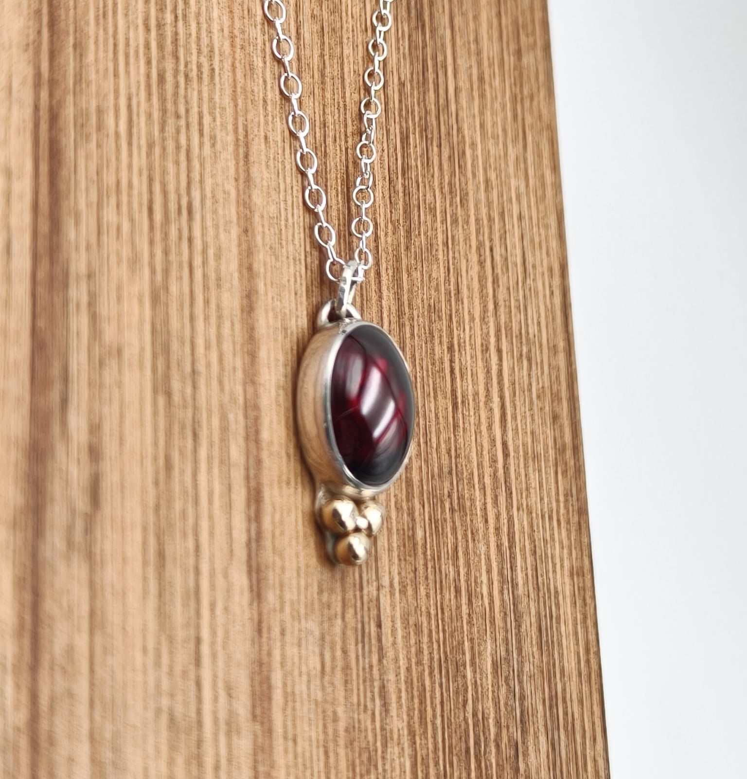 Necklace with a red stone pendant on a wooden surface