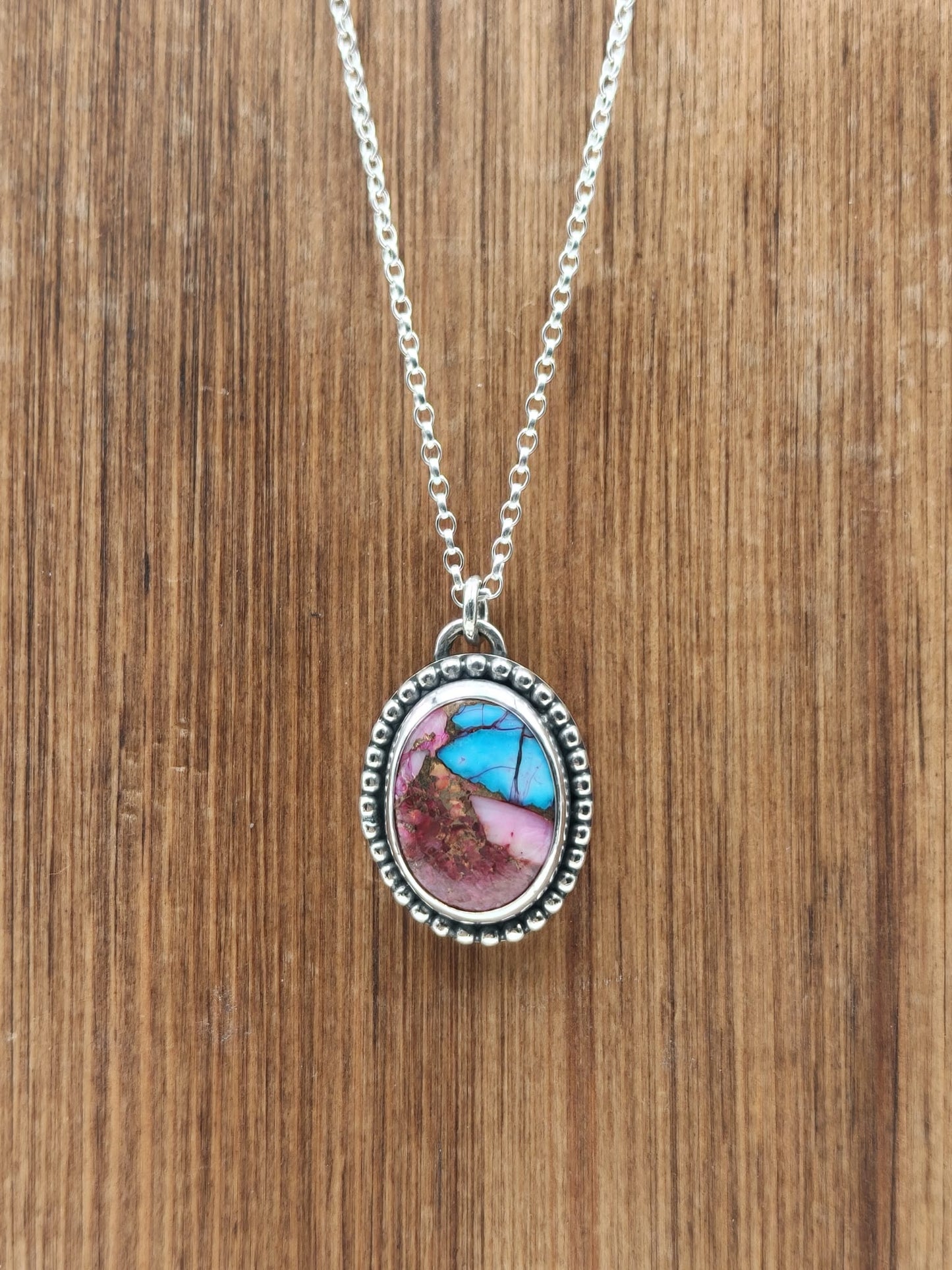 Sterling Silver and Spiny Oyster pendant on wooden display 