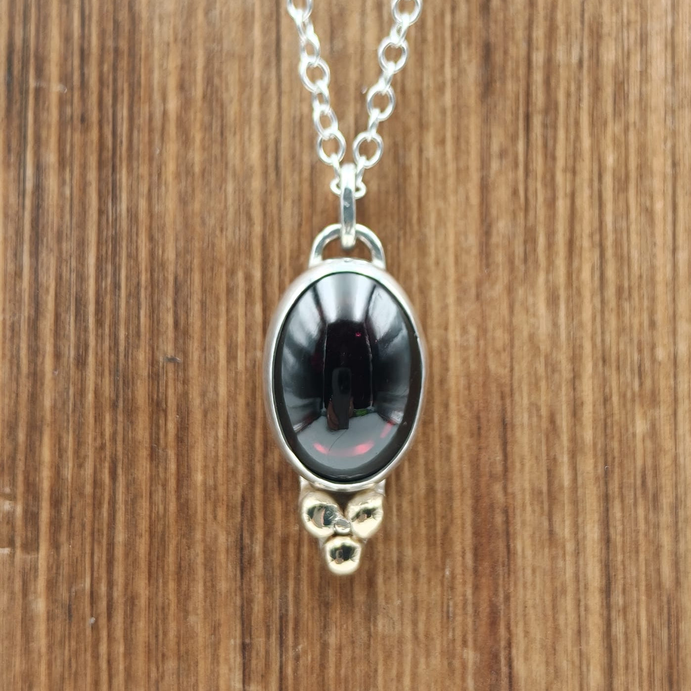 Necklace with a red pendant on a wooden surface