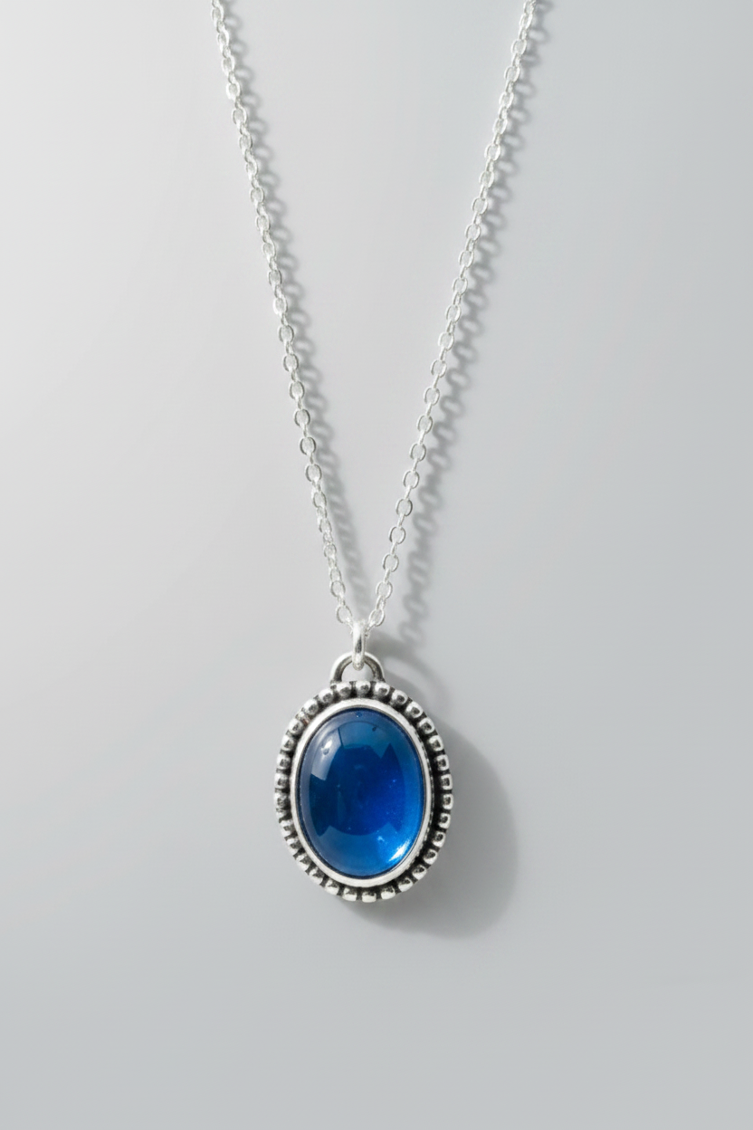 Necklace with blue glass pendant on a light gray background