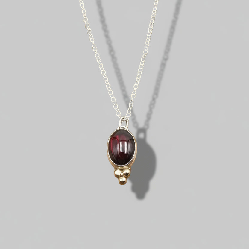 Necklace with a red gemstone pendant on a gray background